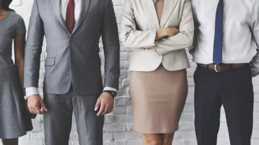 People in business attire standing against a brick wall