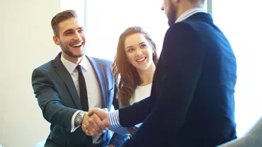 Three people in business attire greeting each other with a handshake.