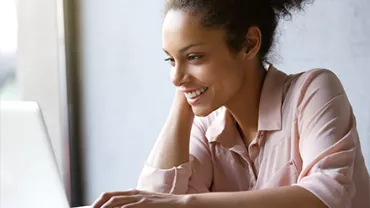 Person smiling while using a laptop.