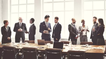 Group of people in business attire discussing around a table.